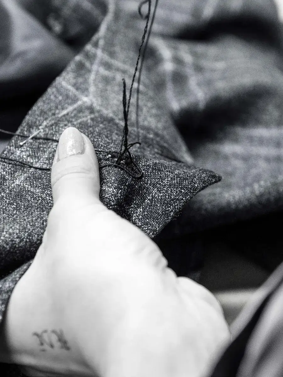 Kockás bespoke öltöny zakójának kézi varrása közelről